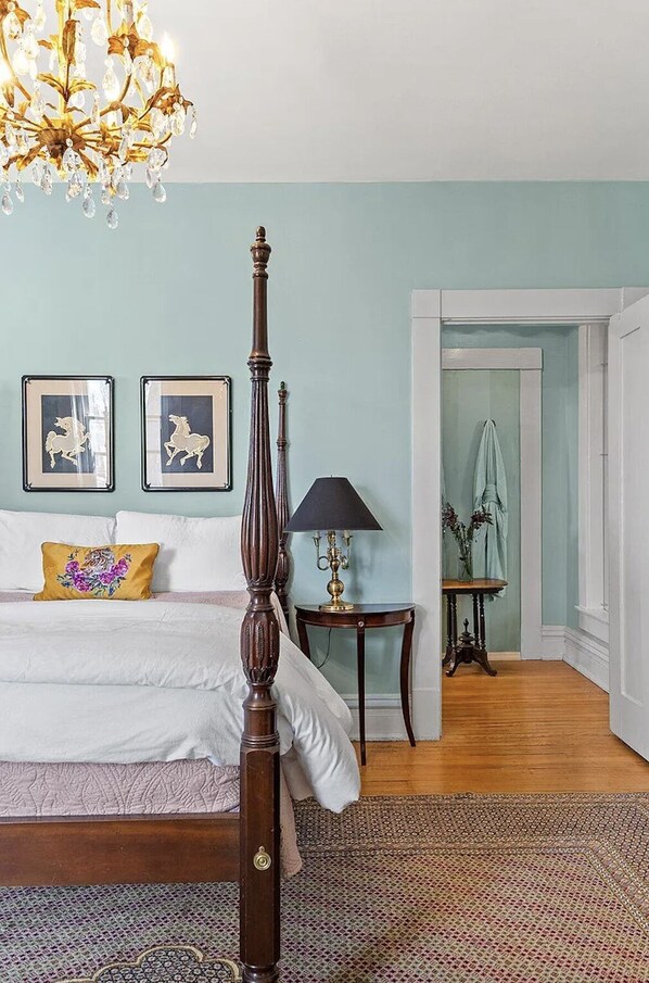 A bedroom with a four-poster bed, a chandelier, a nightstand with a lamp, and two framed pictures on the wall. - Historic Ward Home - Experience history in the horse country! 5br 5.5bth (Lexington)