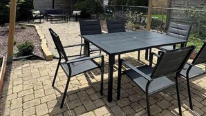 An outdoor patio with a table and chairs, surrounded by a wooden fence and trees. - Elegant Brady St Home with Excellent Walkability (Milwaukee)