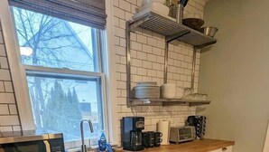 A kitchen with white cabinets, a microwave, a coffee maker, and a dishwasher. - Elegant Brady St Home with Excellent Walkability (Milwaukee)