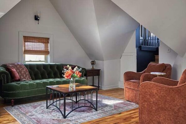 A loft-style living room with a green sofa, a wooden coffee table, and a red armchair. - Gorgeous Brewers Hill Victorian (Milwaukee)