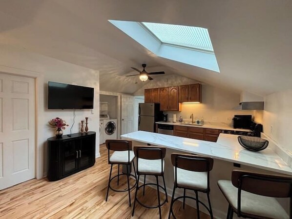 A modern kitchen with a central island, bar stools, a ceiling fan, and a skylight. - Gorgeous Brewers Hill Victorian (Milwaukee)