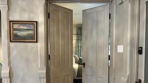 A hallway with a wooden floor leading to a bedroom with a bed and a nightstand. - Gorgeous Brewers Hill Victorian (Milwaukee)