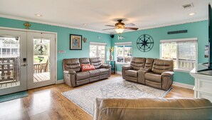 A living room with two leather recliners, a sofa, a ceiling fan, and a large window. - Waterfront Bay St Louis Home w/ Private Dock! (Bay St Louis)
