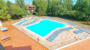 Une piscine avec des chaises longues et un bâtiment en arrière-plan.