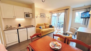 Un espace de vie compact comprenant un coin cuisine, un canapé, une table à manger et un téléviseur.