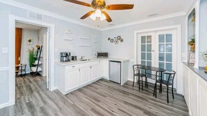 A modern kitchen with white cabinets, a microwave, and a dining area with a table and chairs. - Luxury 3 Bedroom Home, Quiet Neighborhood, Pet Friendly, & Near Beaches!  (Clearwater)