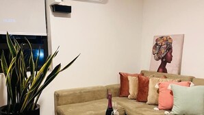 A living room with a beige sofa, a round coffee table, a potted plant, and a painting on the wall. - Tezza Polo Aparts (Santiago de Surco)