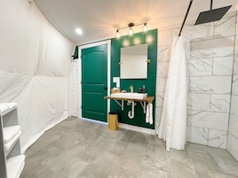 Un baño con puerta verde, un lavamanos blanco con espejo y cortina de ducha.