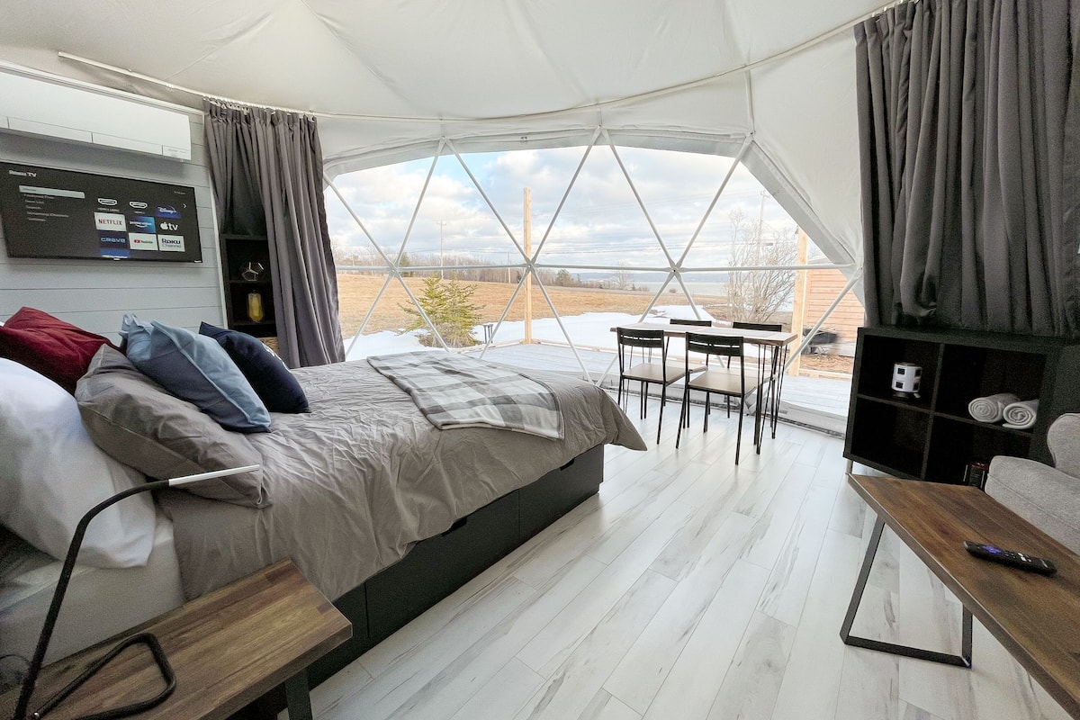 Um quarto tipo tenda com uma cama, uma televisão, uma mesa e vista para o exterior.