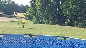 Ein Swimmingpool mit blau gefliestem Becken, umgeben von einem weißen Zaun.