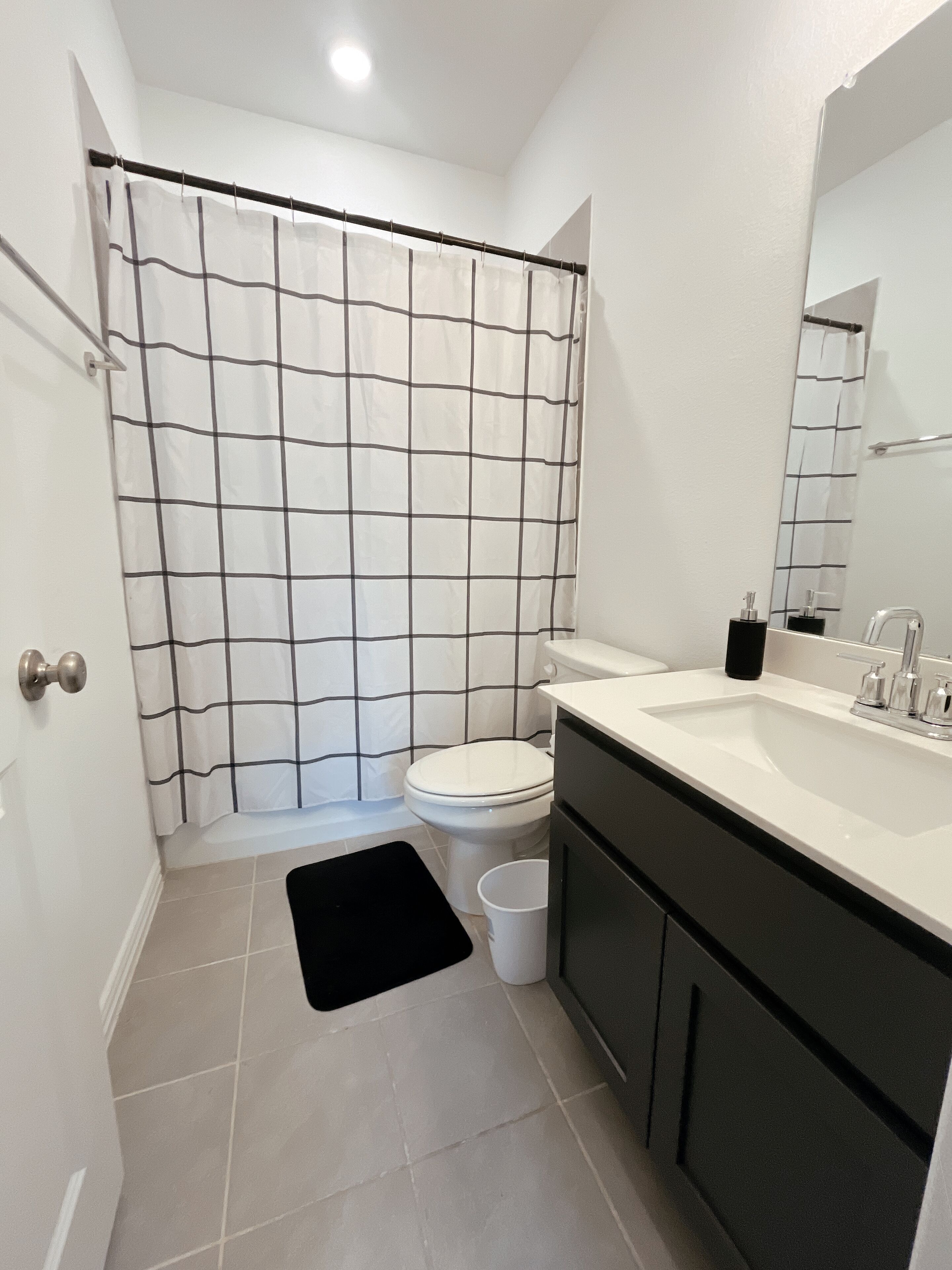 A bathroom with a white toilet, a black bathtub, and a white sink with a mirror above it.