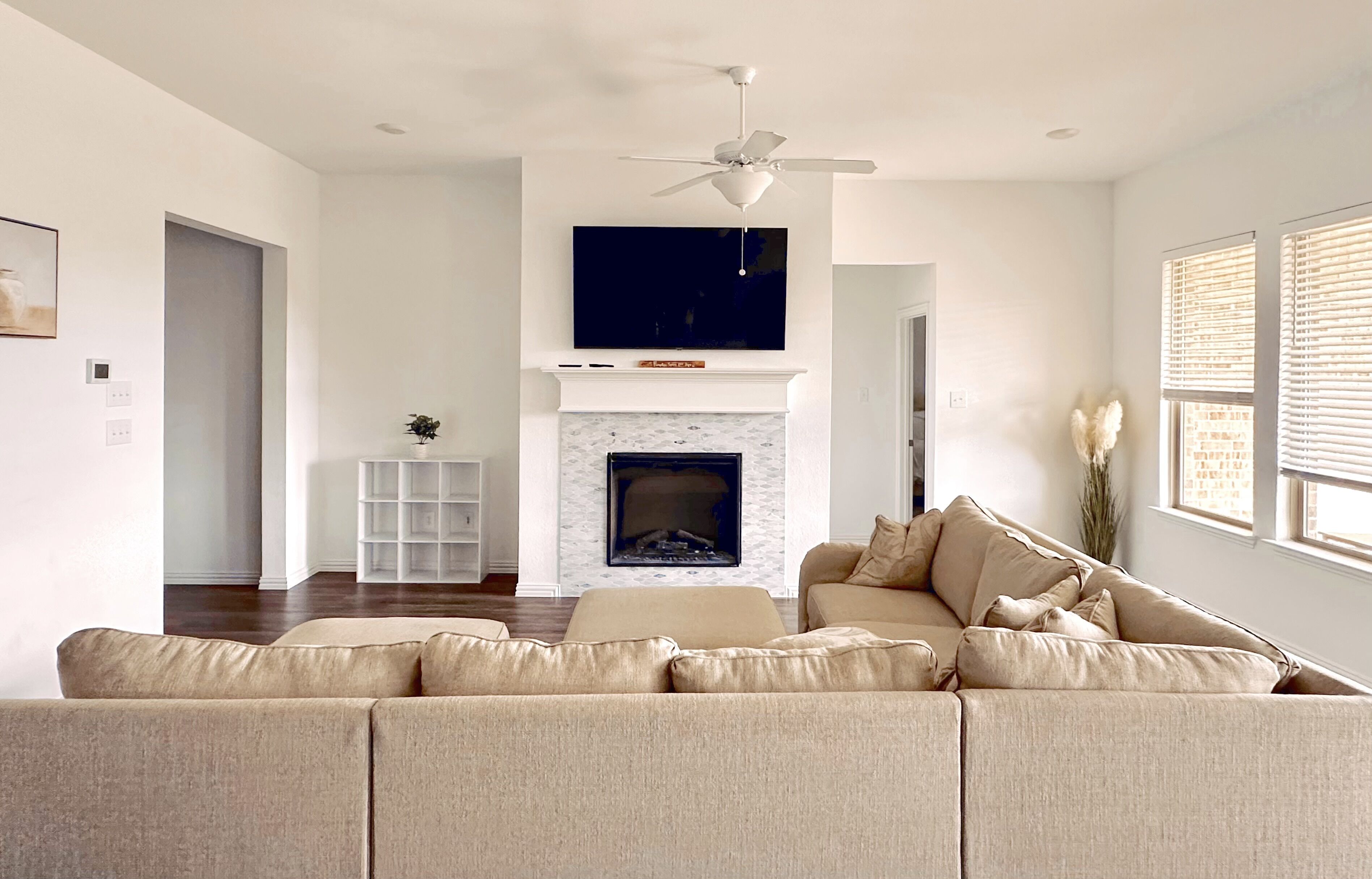 Ein modernes Wohnzimmer mit Ecksofa, Kamin und Deckenventilator.