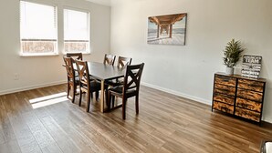 A dining room with a wooden table and chairs, a painting on the wall, and a cabinet with a plant. - House in North Fort Worth (Haslet)
