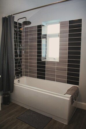 A modern bathroom with a freestanding bathtub, a showerhead, and a window above the bathtub. - Cosy Deluxe 2 bedroom terraced house near centre (Sunderland)