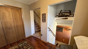 A hallway with a wooden floor, a grey couch, and a staircase leading to another room. - Large  fully furnished,centrally located northern Minnesota retreat . (Embarrass)