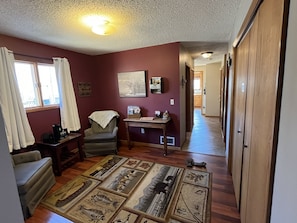 A living room with a wooden floor, a chair, a table, and a rug with animal prints.