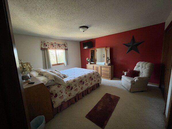 A bedroom with a bed, dresser, chair, and a star decoration on the wall.