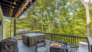 Una terrazza con posti a sedere all'aperto, una vasca idromassaggio e un braciere.