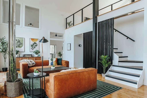 Un salon moderne avec un canapé marron, une table basse et un escalier doté de rampes noires.