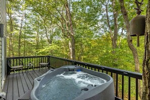 Un bain à remous sur une terrasse en bois, entouré d’arbres.