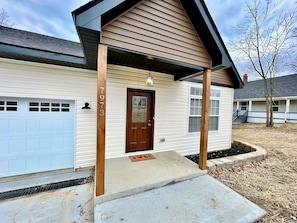 A single-story house with a front porch, a garage, and a small front yard. - Beautiful NEW Ranch Home with a large deck & games (West Chester Township)