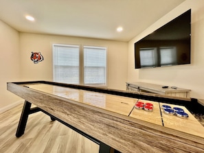 A pool table with a tiger logo, two windows with blinds, and a mounted TV. - Beautiful NEW Ranch Home with a large deck & games (West Chester Township)