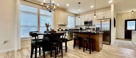 Una cocina moderna con una isla central, piso de madera e iluminación colgante.