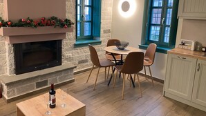 Un coin repas chaleureux avec une cheminée, une table entourée de chaises et une bouteille de vin.