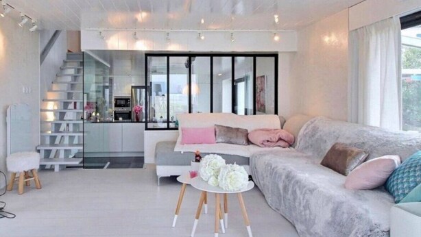 A modern living room with a sofa, a small round table, and a staircase leading to a kitchen. - Villa Cocooning Les Pieds Dans l eau (Saint-Pierre-Quiberon)
