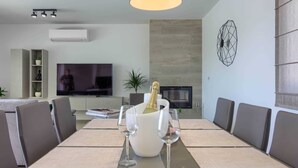 Una sala moderna con comedor, televisor de pantalla plana, chimenea y un elemento decorativo en la pared.