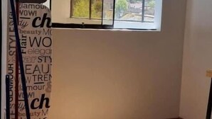 Una habitación con un amplio ventanal, suelo de madera y un perchero en el techo.