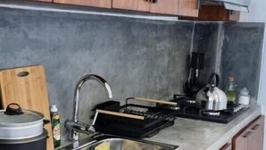 Una cocina con armarios de madera, un lavamanos de acero inoxidable, una estufa y una tabla de cortar.