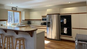 A modern kitchen with a central island, stainless steel appliances, and wooden accents. - Woodzy Retreat Getaway (Black Butte Ranch)