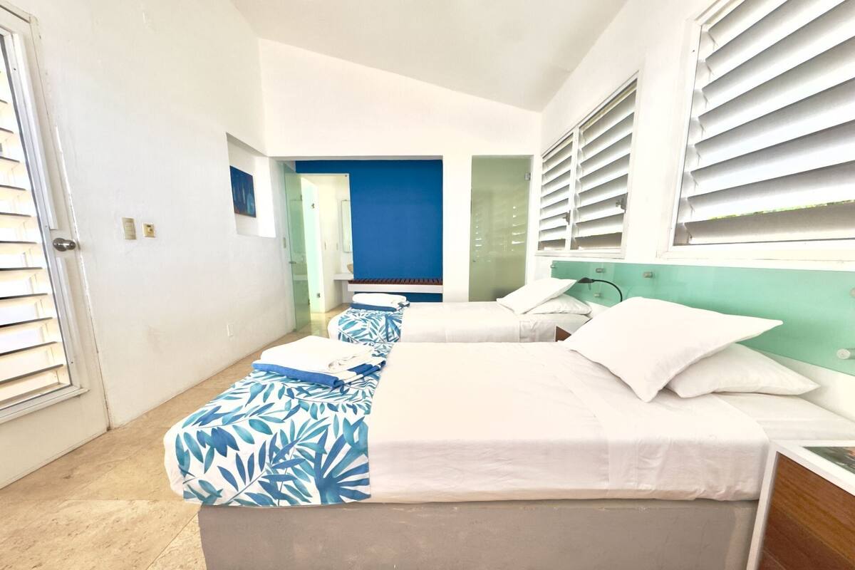 Habitación de hotel con dos camas, baño y vista a la calle.