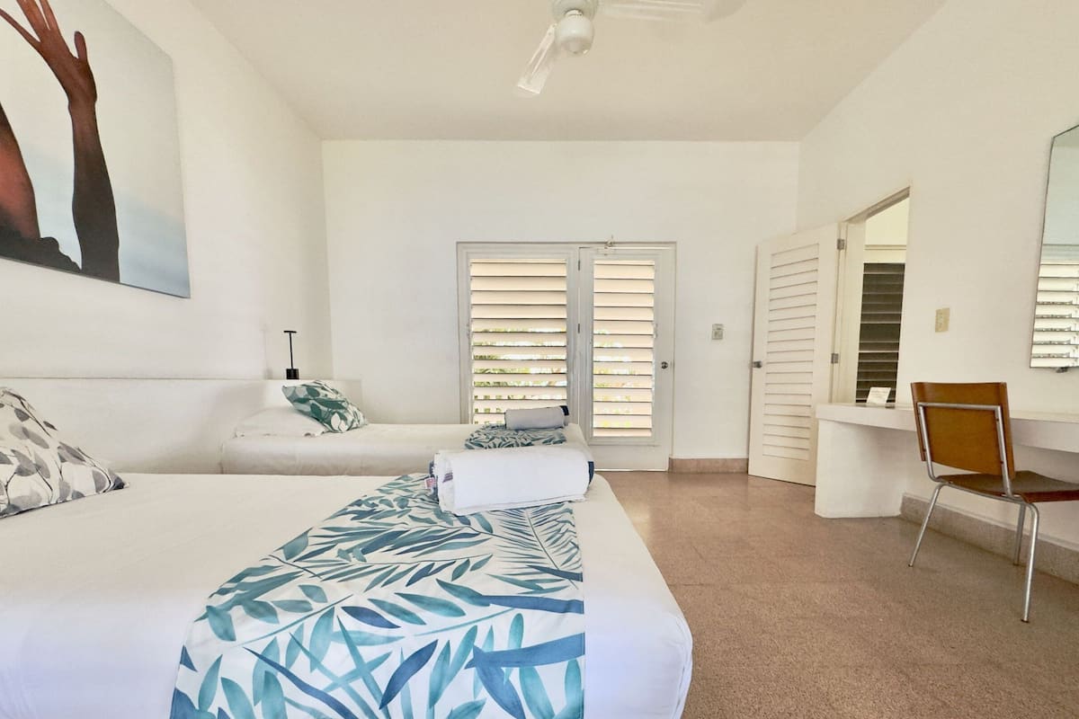 Un dormitorio con cama, una silla, un escritorio y una puerta que da a otra habitación.