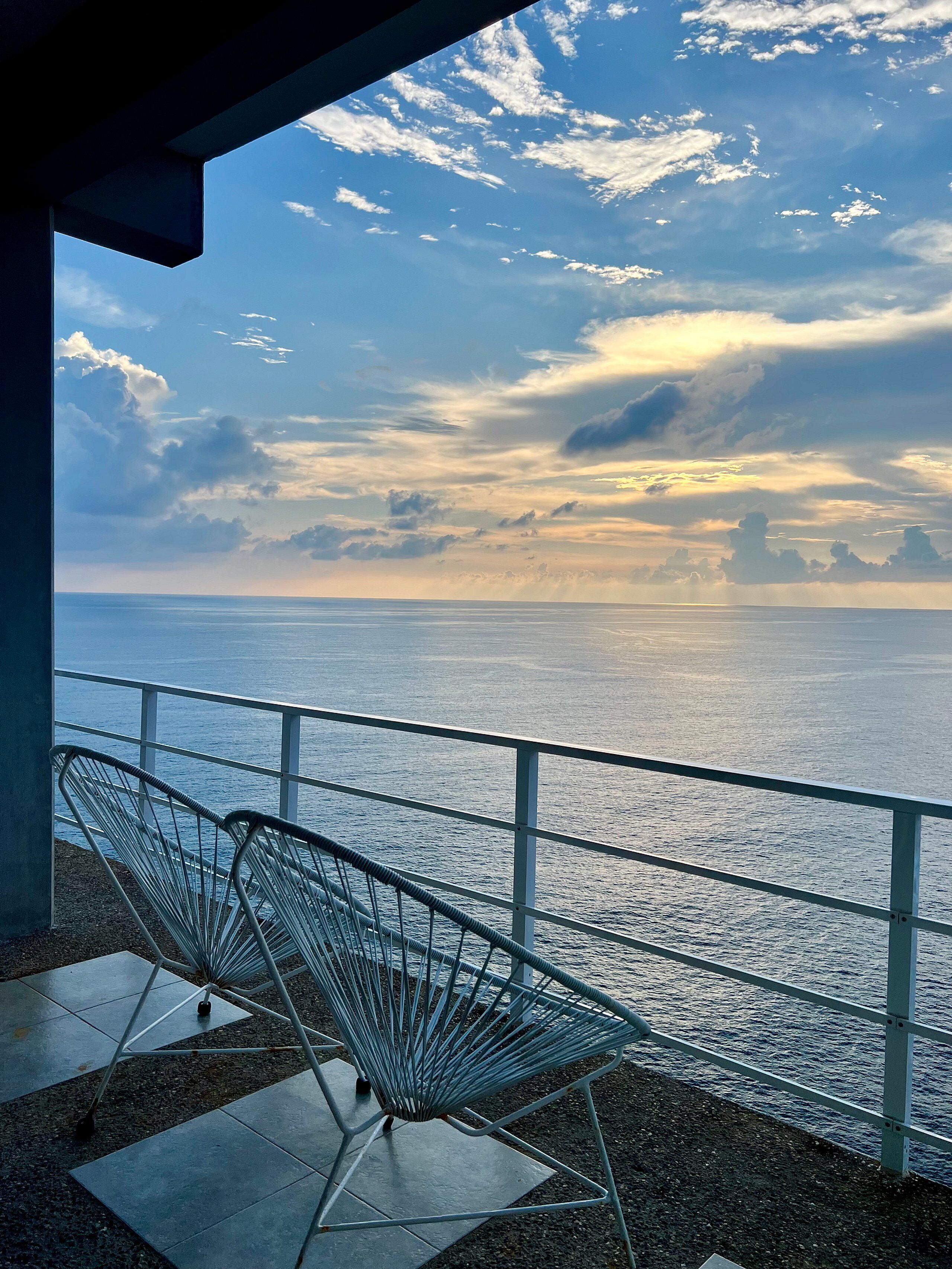 A balcony with metal chairs overlooking a body of water.