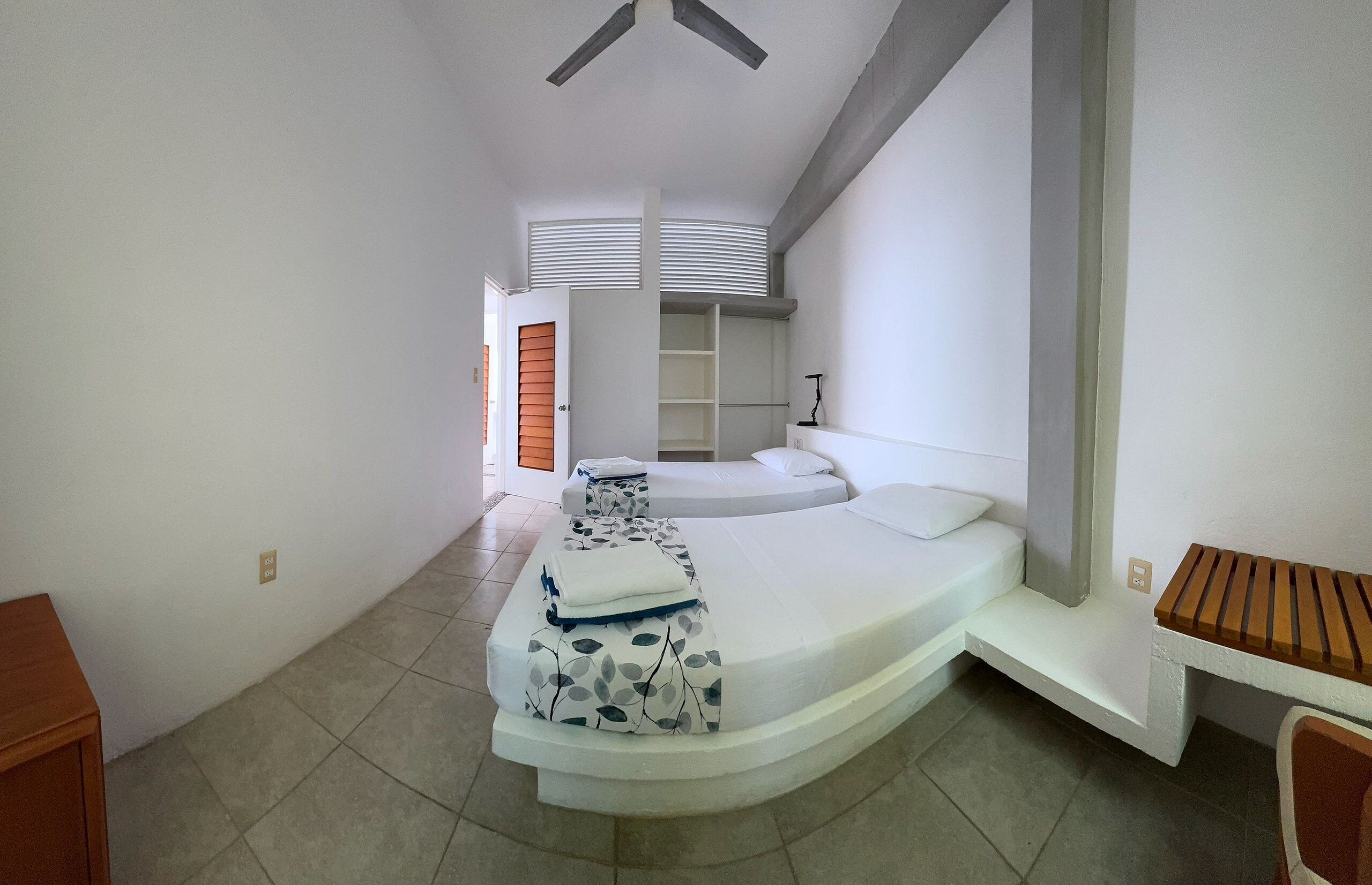 A bedroom with a curved bed, a desk, and a chair.