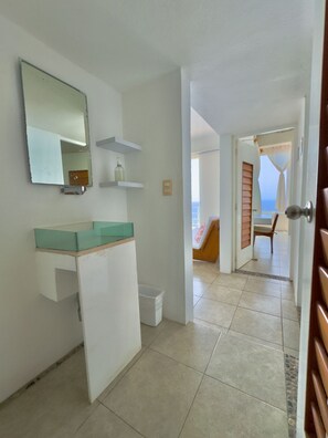 Une salle de bain avec un miroir, une étagère et un lavabo.