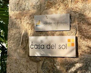 Twee borden op een stenen muur, waarvan de één 'casas del acantilado' vermeldt en de andere 'casa del sol'.