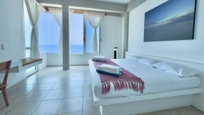 Un dormitorio con cama, escritorio, lámpara de pie y un cuadro en la pared.
