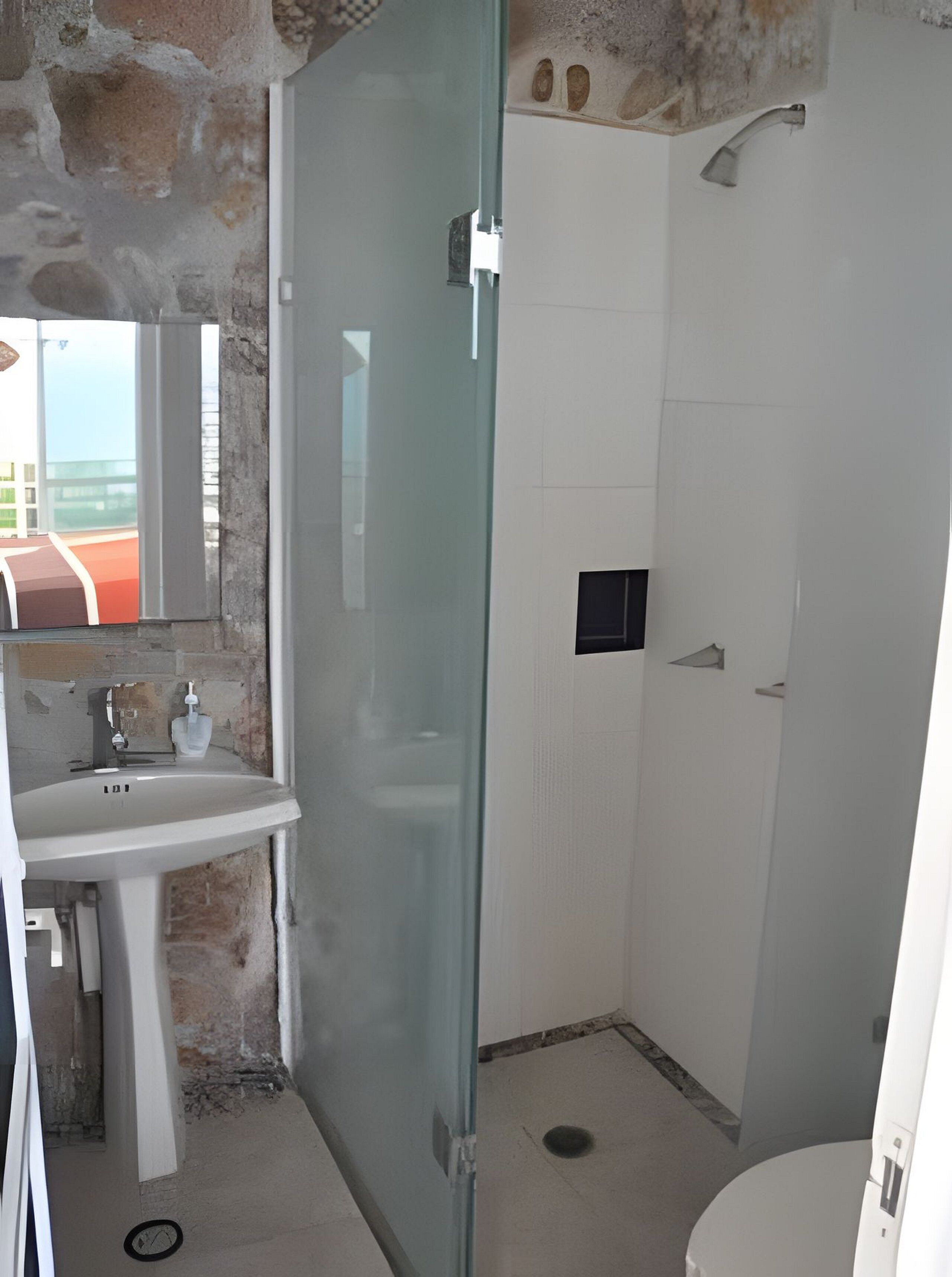 A bathroom with a glass-enclosed shower, a sink, and a mirror.