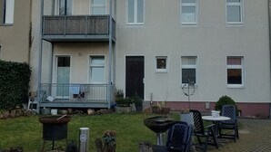 A multi-story residential building with a balcony, a small garden area, and outdoor seating. - 2 Zimmer-wohnung am Landesmuseum für Vorgeschichte (Halle)
