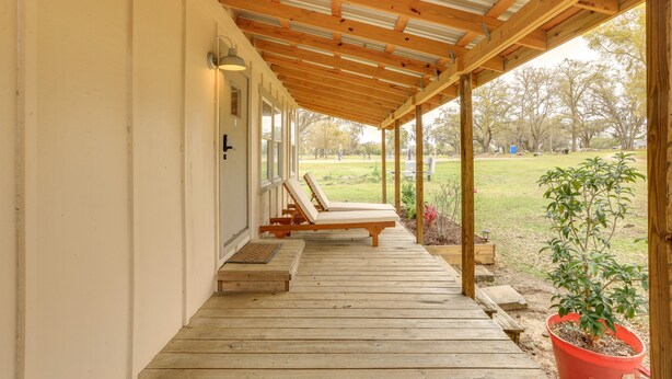 A covered porch with wooden flooring and two lounge chairs. - Cottage on 80-Acre Farm near WEC & Devil's Den (Morriston)
