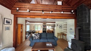 A cozy living room with a wooden ceiling, a blue sofa, a wooden coffee table, and a fireplace.