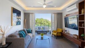 A modern living room with a sofa, armchair, coffee table, and TV. - Increible y Moderno Departamento con Mucho Espacio, Ideal Para Quien sea (Bucerías)