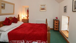 A bedroom with a bed, a nightstand, a dresser, and a window with blinds.