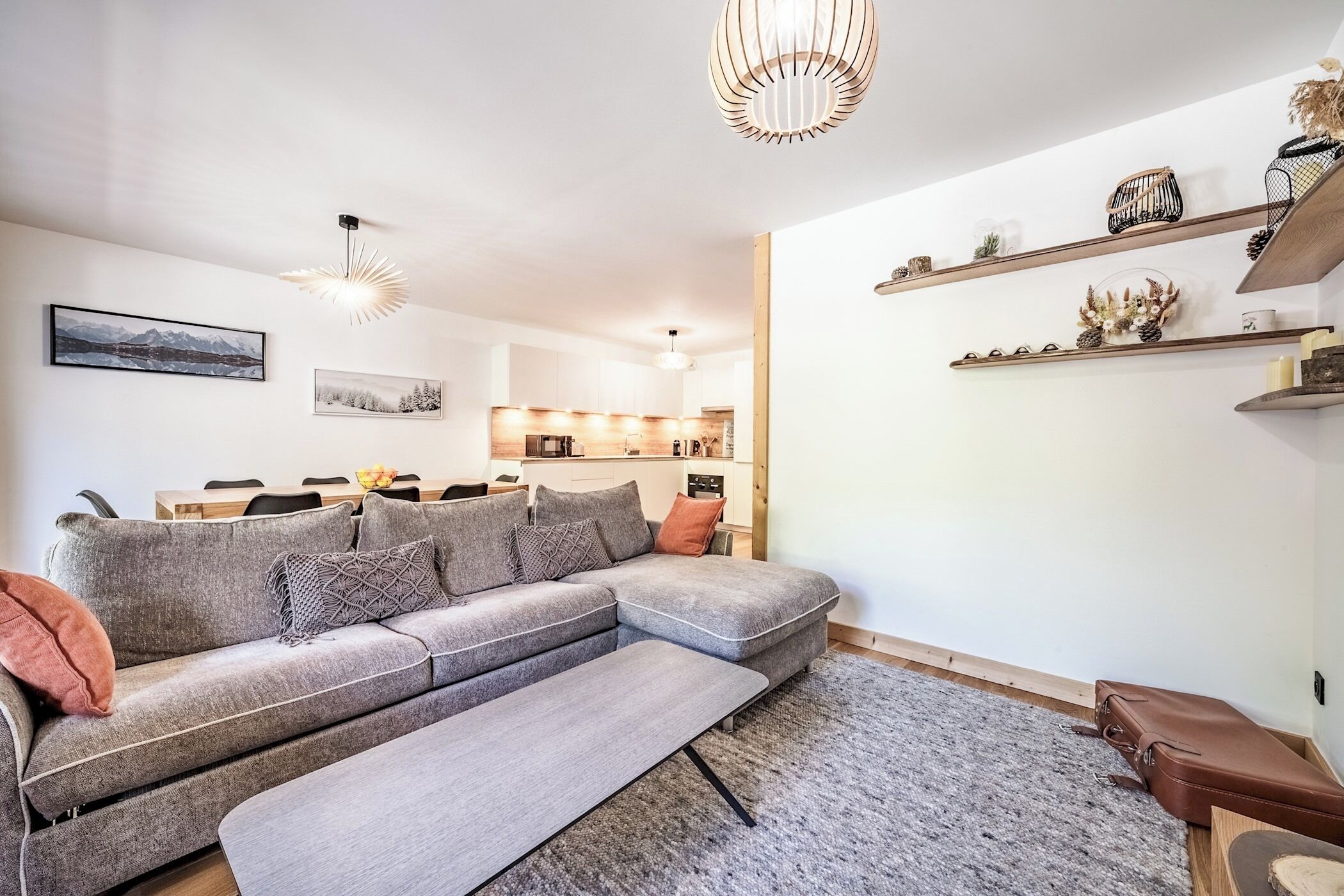 Un salon moderne avec un canapé d’angle, un banc et un coin repas comprenant une table et des chaises.