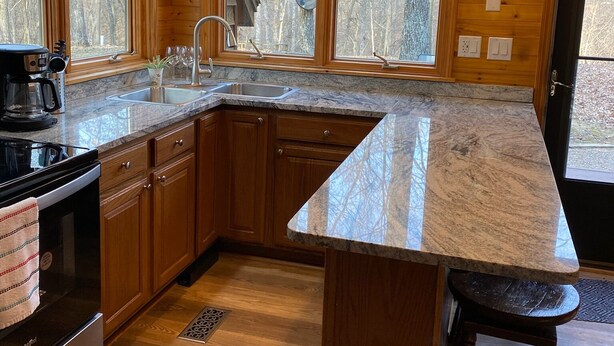 A modern kitchen with wooden cabinets, a large island, and a built-in stove.