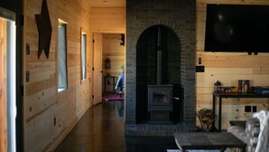 Ein Holzinnenraum mit Kamin, einem an der Wand montierten Fernseher und einer Sternverzierung an der Wand.