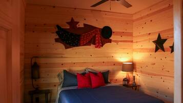 A cozy room with a bed, a ceiling fan, and wooden walls.